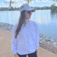 Figure wearing white embossed sweater with white trucker cap with grey logo